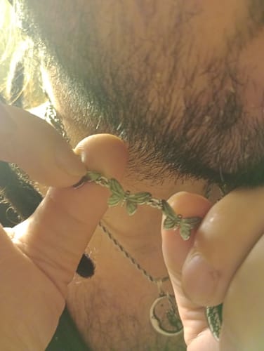 Close-up of a customer holding the Butterfly Necklace to display the detailed butterfly links.
