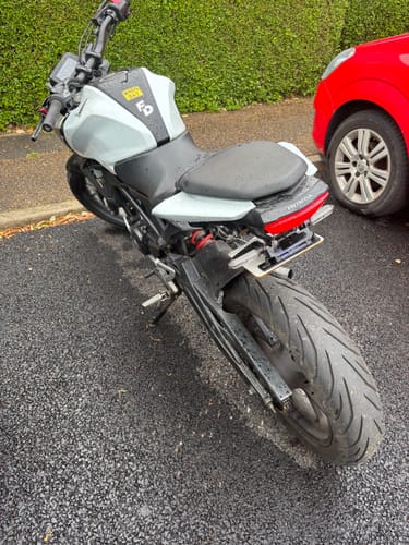 Reviewer's Honda CB125R with a minimal tail tidy installed, showing the license plate flipped up under the seat.