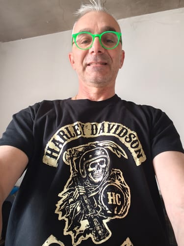 Un client portant le T-shirt noir Faucheuse HC avec le motif d'un squelette à casque et une faux.