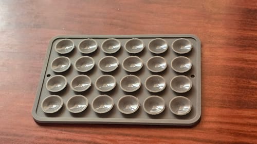 Reviewer's grey StickyPod showing its 24 suction cups on a wooden surface.