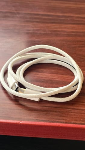 Customer's white, braided Casence Armor Type C to C charging cable coiled on a wooden surface.