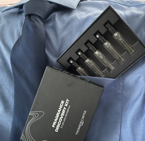 Customer's Fragrance Discovery Kit with its black box and five sample vials displayed on a shirt and tie.