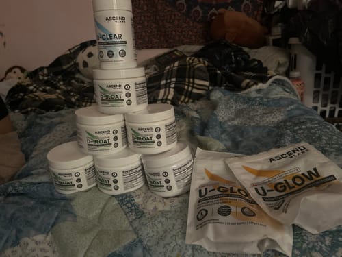 Customer's large collection of D-BLOAT containers stacked in a pyramid on a bed.
