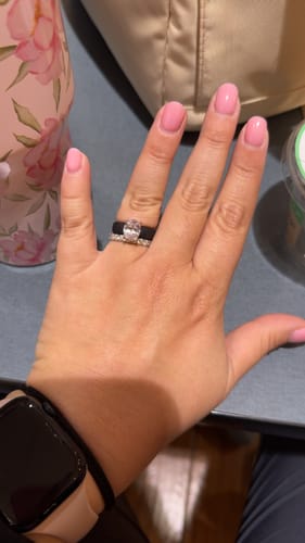 Customer's hand wearing the black Silicone Ring with its oval-cut stone, stacked above a pavé band.