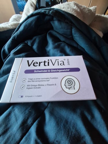 Ein Kunde zeigt die lila Schachtel von VertiVia intens auf einer dunklen, weichen Decke.