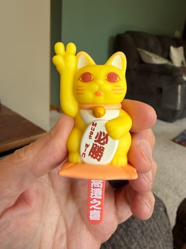 Customer holding a yellow Lucky Cat figurine from the Blessing Lot Pot blind box series.