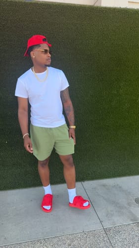 Customer wearing bright red Remastered DracoSlides with socks and green shorts outdoors.