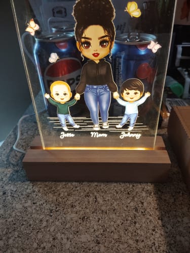 Customer's personalized acrylic LED night light showing a cartoon mother and two sons on its wooden base.