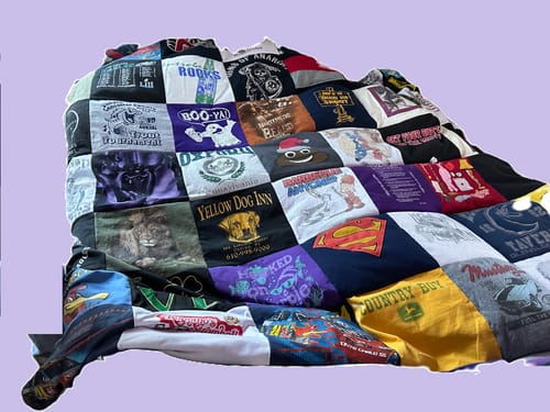 Customer's colorful Premium T Shirt Quilt made from various t-shirts, draped over a surface.