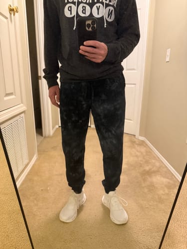 Customer in a mirror selfie wearing the relaxed-fit 80Eighty® TieDye Black Fleece Pant.