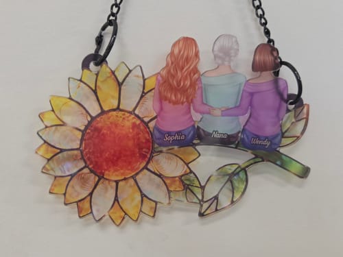 Customer's personalized sunflower suncatcher with three figures named Sophia, Nana, and Wendy sitting on a stem.