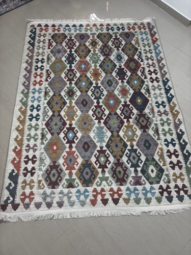 Customer's Afghan Kilim Printed Rug with a colorful geometric pattern laid out on a tile floor.