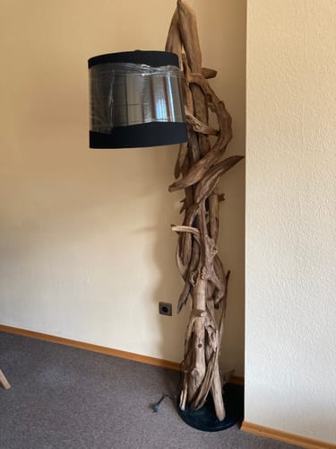 Rezensent zeigt die aufgestellte Wurzelholzlampe MORGAN mit dem noch verpackten schwarzen Lampenschirm.