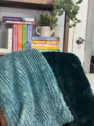 Reviewer's two-sided blanket showing the textured spruce side and plush cypress side, draped on a chair.