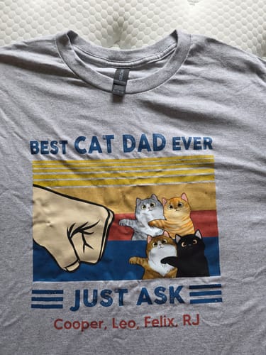 Reviewer's gray personalized cat dad shirt laid flat, showing a fist bump graphic with four cats and personalized names.