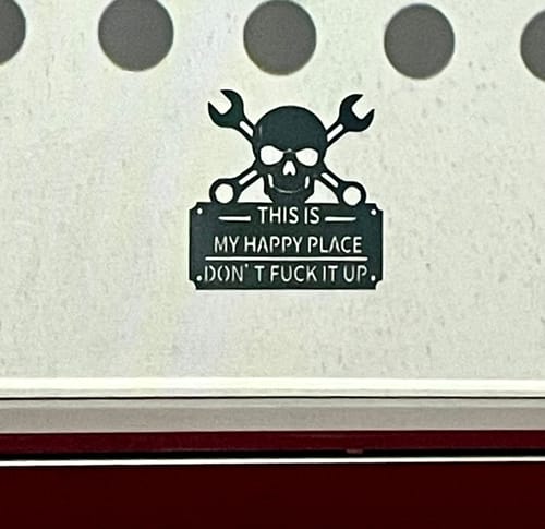 Reviewer's black metal wall art sign with a skull and wrenches that reads 'This Is My Happy Place Don't Fuck It Up'.
