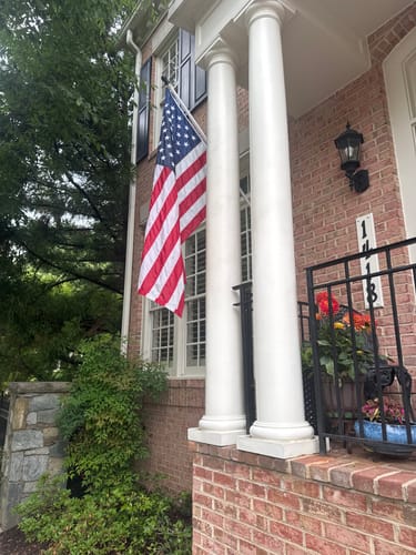 Customer's Heavy Duty American Nylon Flag hanging from the second story of a brick house.