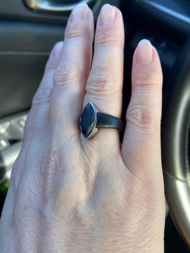 Close-up of a customer's hand wearing a black silicone ring with a metal marquise frame.
