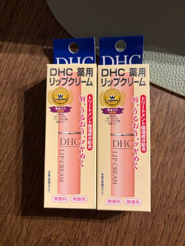 Customer's two boxes of DHC Medicated Lip Cream standing side-by-side on a wooden surface.
