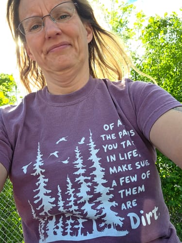 Reviewer outdoors wearing the purple Paths In Life T-shirt, showing the front graphic with trees and text.