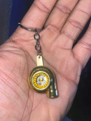 Reviewer holding the shiny gold TURBO KEYCHAIN in the palm of their hand.