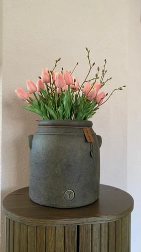 Reviewers mooie roze tulpenboeket in een donkere vaas op een houten bijzettafel.