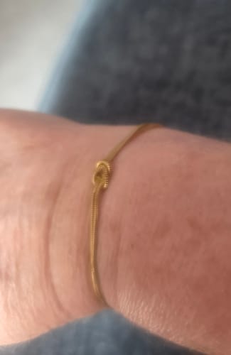 Close-up of a reviewer wearing the gold Forever Knot Bracelet on their wrist.