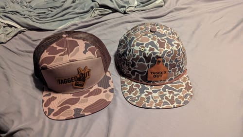 Customer's two Custom Leather Patch Trucker Hats. Both hats feature a camo pattern and a 'Tagged Out' leather patch.