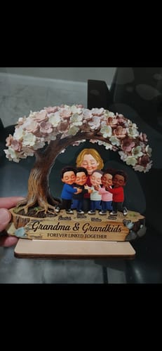 Customer holding the personalized 2-layered wooden plaque showing a grandma and five grandkids under a blossom tree.