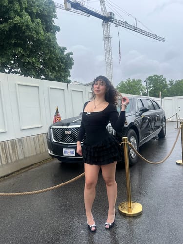 Reviewer posing outdoors in the black Serafina Ruffles Mini Dress, showing its long sleeves and layered skirt.