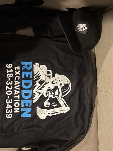 Customer's black long sleeve t-shirt and matching patch hat laid out, showing the custom graphic on the shirt's back.