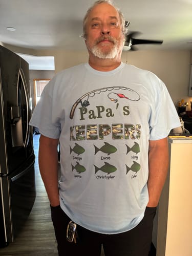Customer wearing the light blue personalized 'Papa's Keepers' fishing shirt with six grandchildren's names on fish.