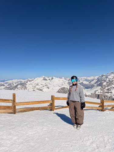 Reviewer standing in the snow wearing the baggy, beige waterproof snow pants.