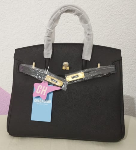Una clienta muestra el bolso negro Carrie, nuevo y con el embalaje protector en las asas y los herrajes.