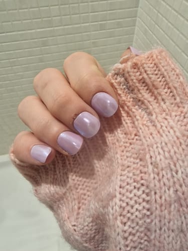 Customer's hand showing off their shiny Lavender Pearlescent nails against a pink knit sweater.
