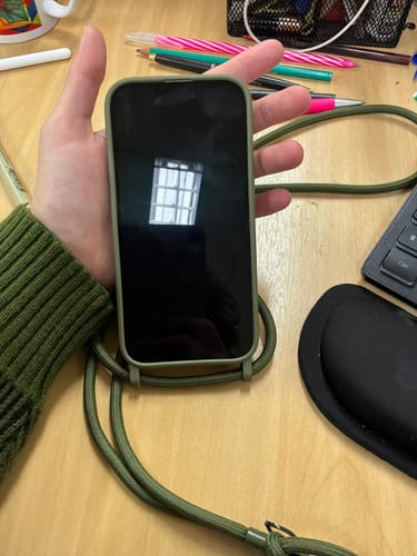 Cliente segurando o celular na Case Verde Musgo com a alça da mesma cor.