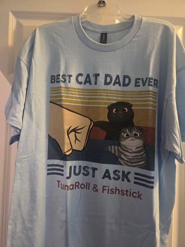 Customer's light blue cat dad shirt showing a "Best Cat Dad Ever" fist bump graphic with personalized names "TunaRoll & Fishstick".