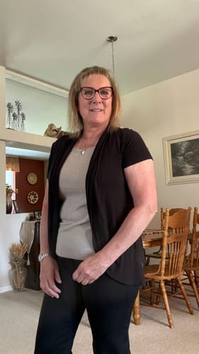 Reviewer in a layered outfit from their Mystery Item purchase, wearing a black cardigan over a light-colored tunic.