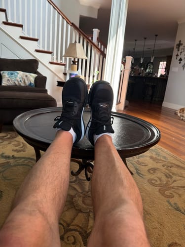 Reviewer relaxing with their feet up on a table, wearing the black CUURT Muuv court shoes.