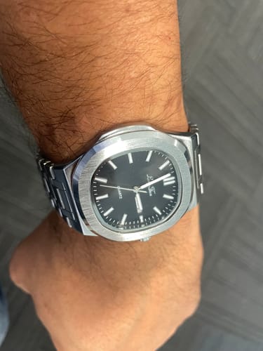 Close-up of a reviewer wearing the steel watch with a black dial on their wrist.