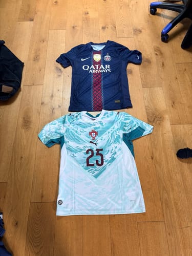 Un client montre le maillot PSG Domicile étalé sur un plancher en bois à côté d'un autre maillot.