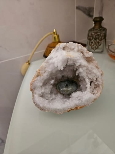Un client montre sa géode de quartz purifiant une petite pierre placée à l'intérieur.