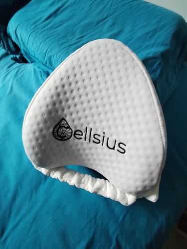 Photo d'un client du coussin orthopédique pour genoux Cellsius, blanc, posé sur un lit.