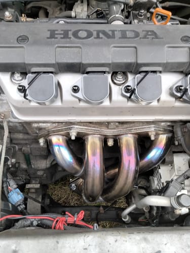 Customer's shiny Exhaust Header installed on a Honda Civic engine, showing colorful pipes.