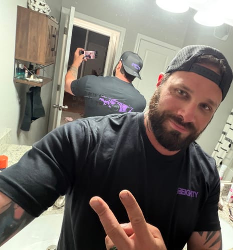 Reviewer taking a mirror selfie to show the front view and perforated back of the black DCG88 Hat.