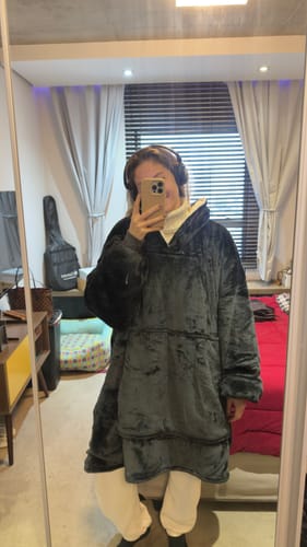 Cliente em uma selfie de espelho, vestindo o macio e grande cobertor vestível Sleepo na cor cinza.