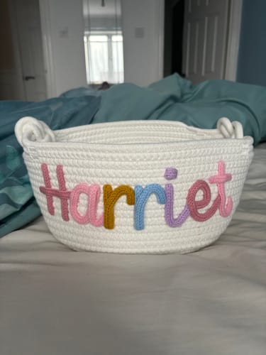 Customer's white personalized knitted basket with the name 'Harriet' in multicolor yarn.