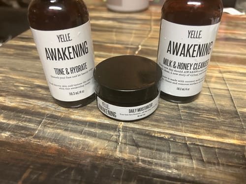 Customer's Awakening Essential 3 Piece System, showing the cleanser, toner, and moisturizer on a wooden surface.