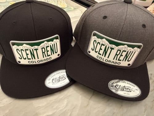 Customer's two Colorado Plate Hats, one black and one dark grey, customized with the text 'SCENT RENU' on the patch.