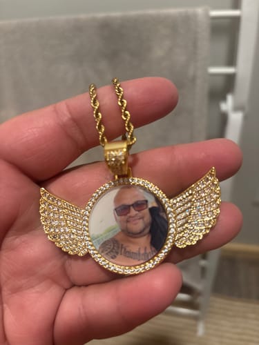 Customer holding their gold-colored Diamond Studded Angel Wing Photo Necklace with a custom picture in the center.